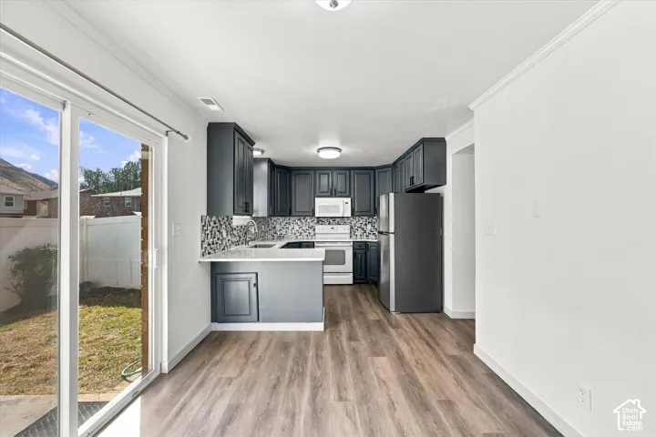 Kitchen with dark cabinetry, white countertops, tile backsplash, and stainless steel appliances