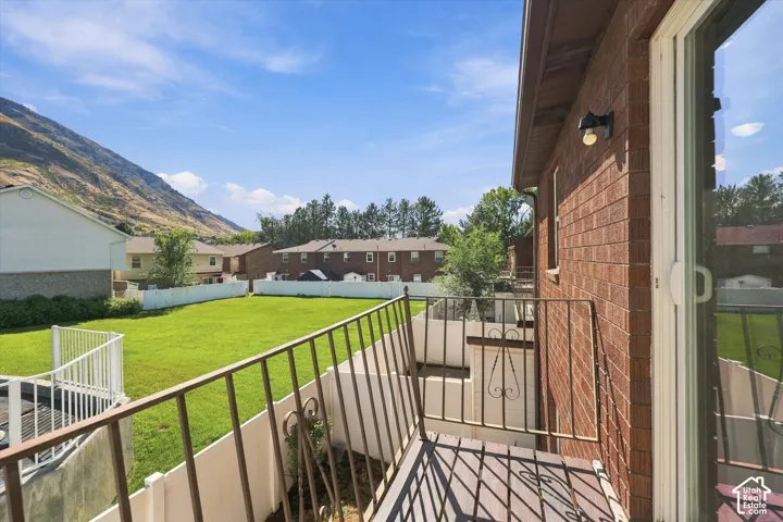 Expansive backyard with a manicured lawn, white privacy fencing, and mountain backdrop