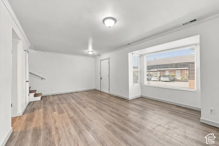 Spacious interior with wood-finish flooring, white walls, and a large bay window with blinds