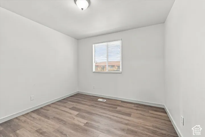 Bedroom #1. Recessed window with horizontal blinds, wood-finish flooring, and ceiling-mounted light fixture