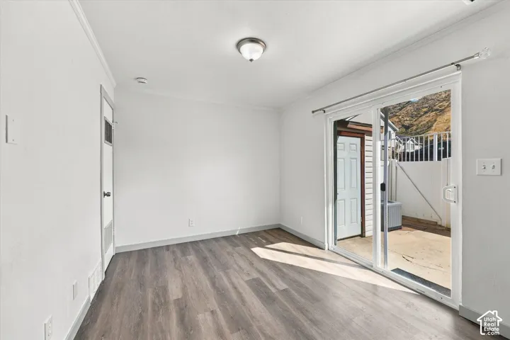 Interior space with wood-finish flooring, white walls, and a ceiling-mounted light fixture