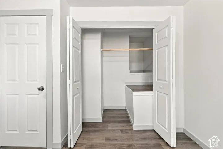 Bedroom #1. Closet with bi-fold doors, wood-finish flooring, built-in shelving, and a hanging rod