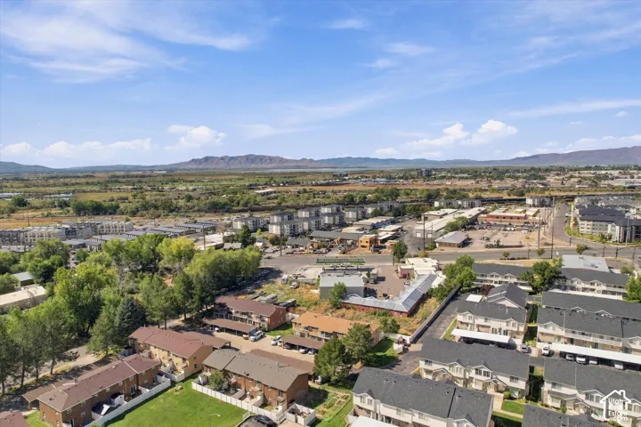 Expansive area featuring residential structures, commercial buildings, mature trees, and a distant mountainous landscape