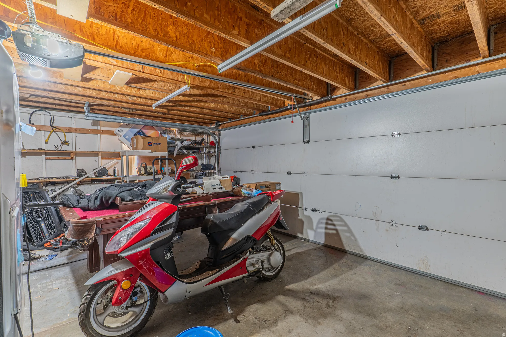Spacious garage featuring concrete flooring and exposed wood ceiling joists