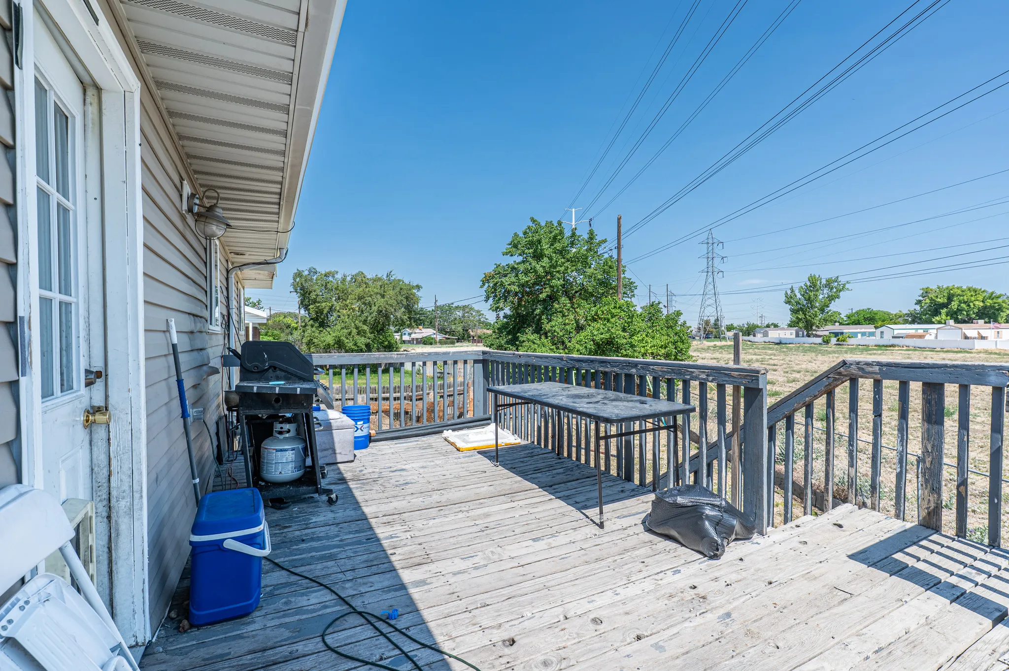 Exterior wood deck with a privacy railing and steps, featuring a vinyl-sided building and a clear sky backdrop