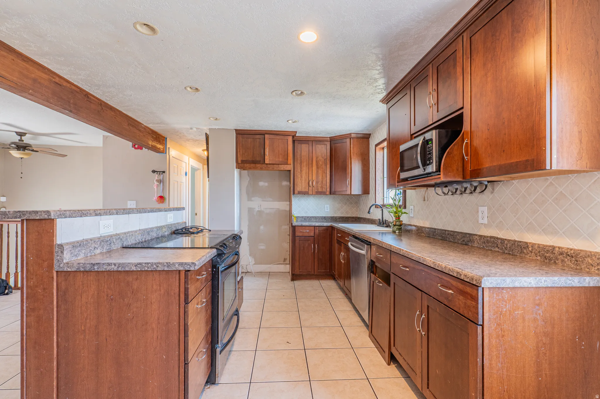 Kitchen featuring wood cabinetry, light-colored tile flooring, and a built-in microwave