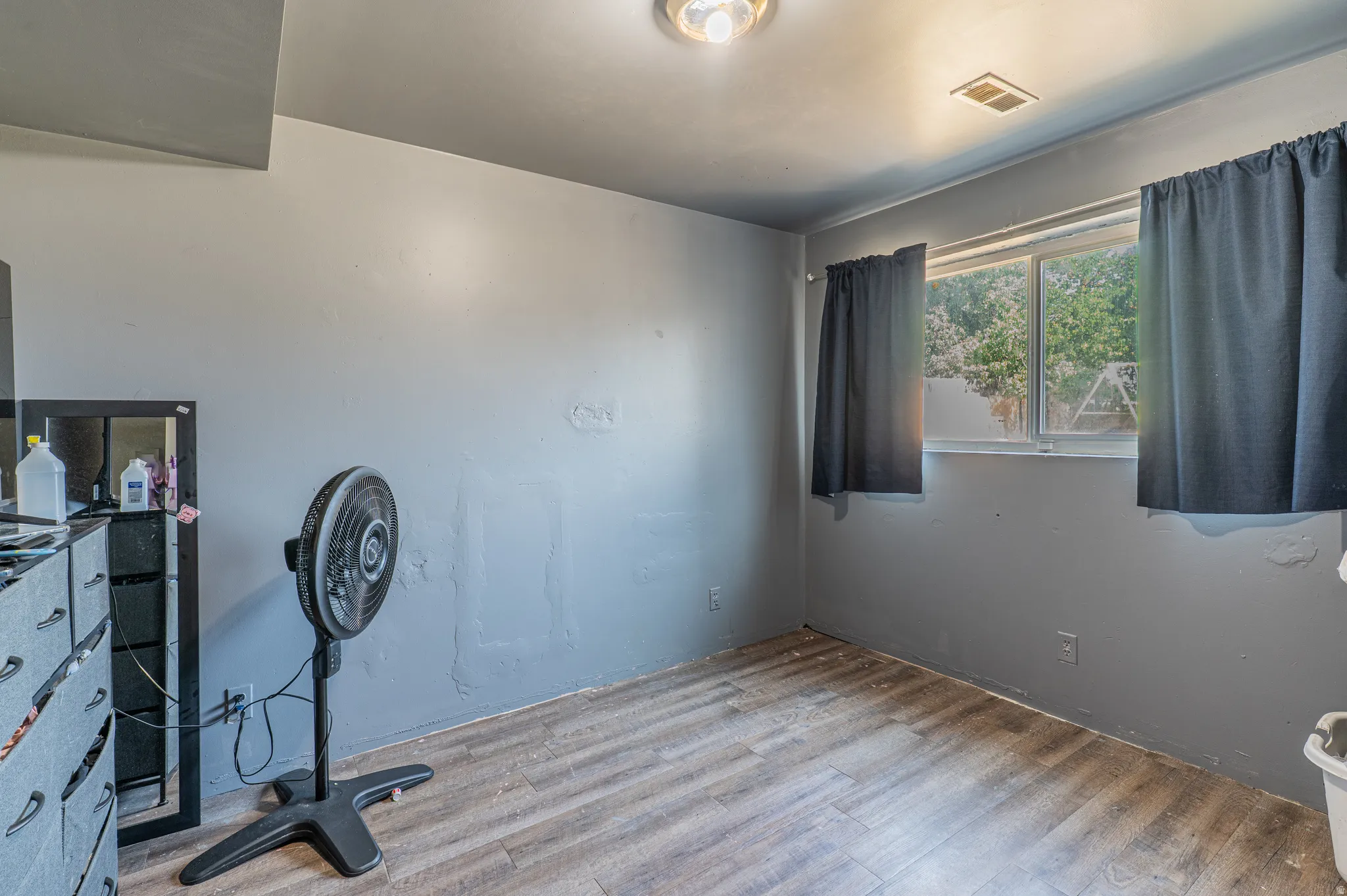 Room featuring wood-finish flooring, a window providing natural light, and a ceiling-mounted light fixture