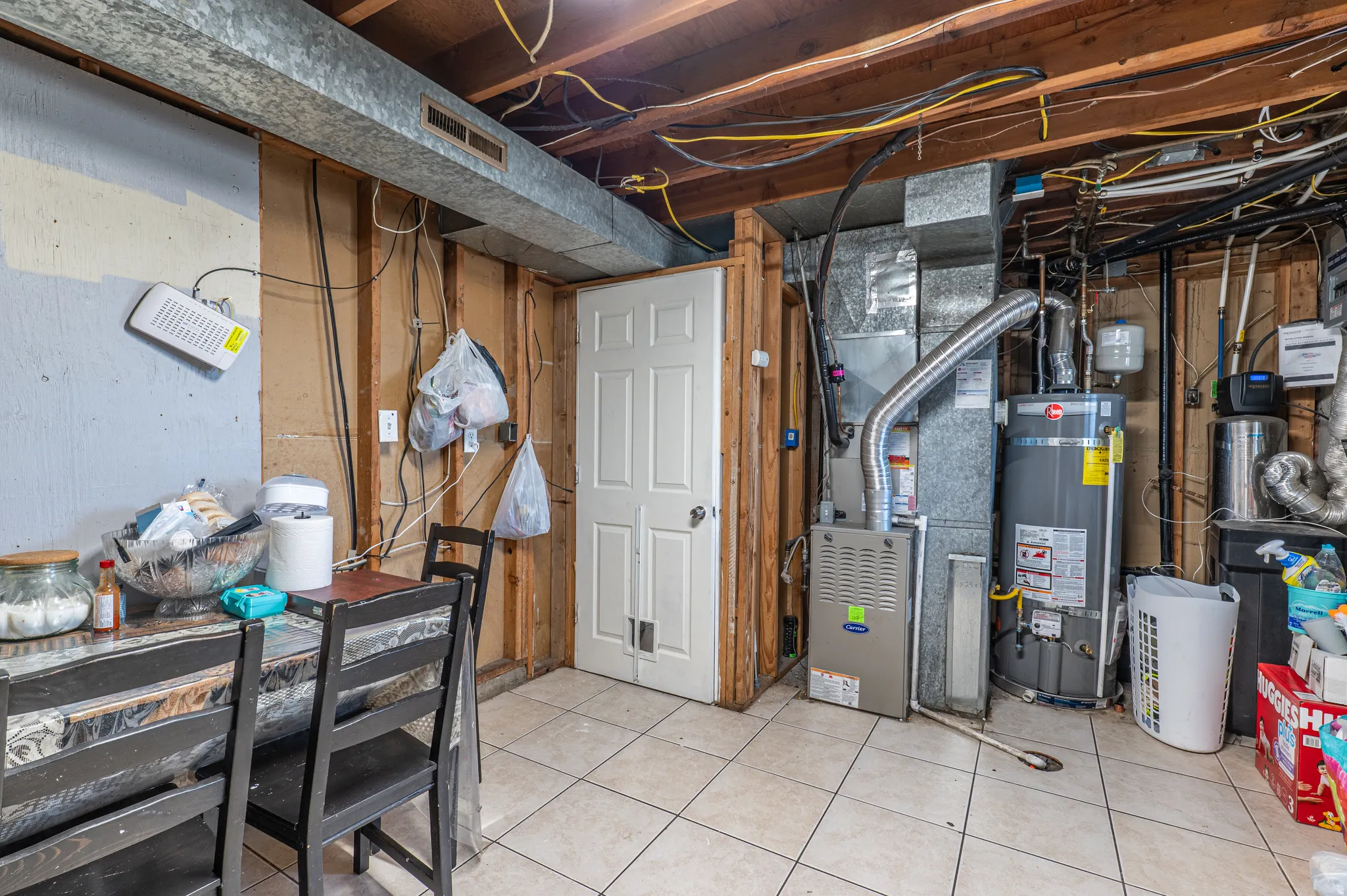 Utility room featuring a furnace, water heater, exposed ductwork, and ceiling joists