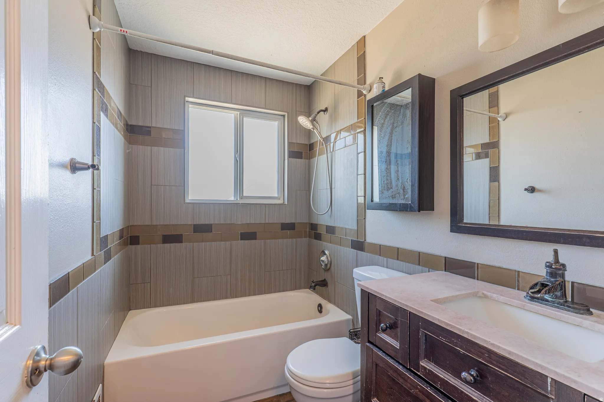 Contemporary bathroom featuring a tiled shower surround with accent bands, a built-in window, and a white bathtub