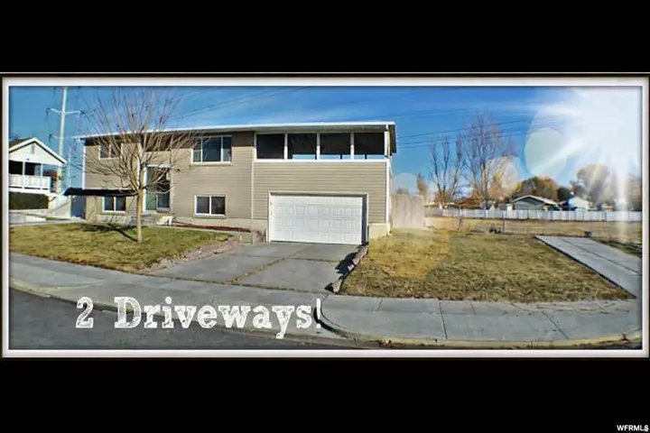 Split-level residence featuring a two-car garage, multiple windows, and two distinct concrete driveways