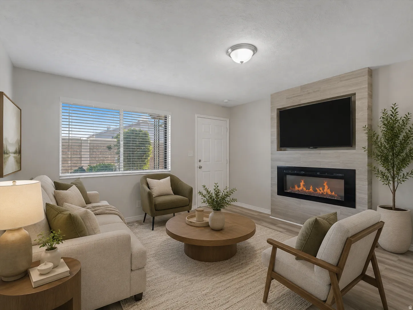 Living area featuring a modern fireplace with a tiled surround, wood-finish flooring, a contemporary ceiling light fixture, and a window with blinds