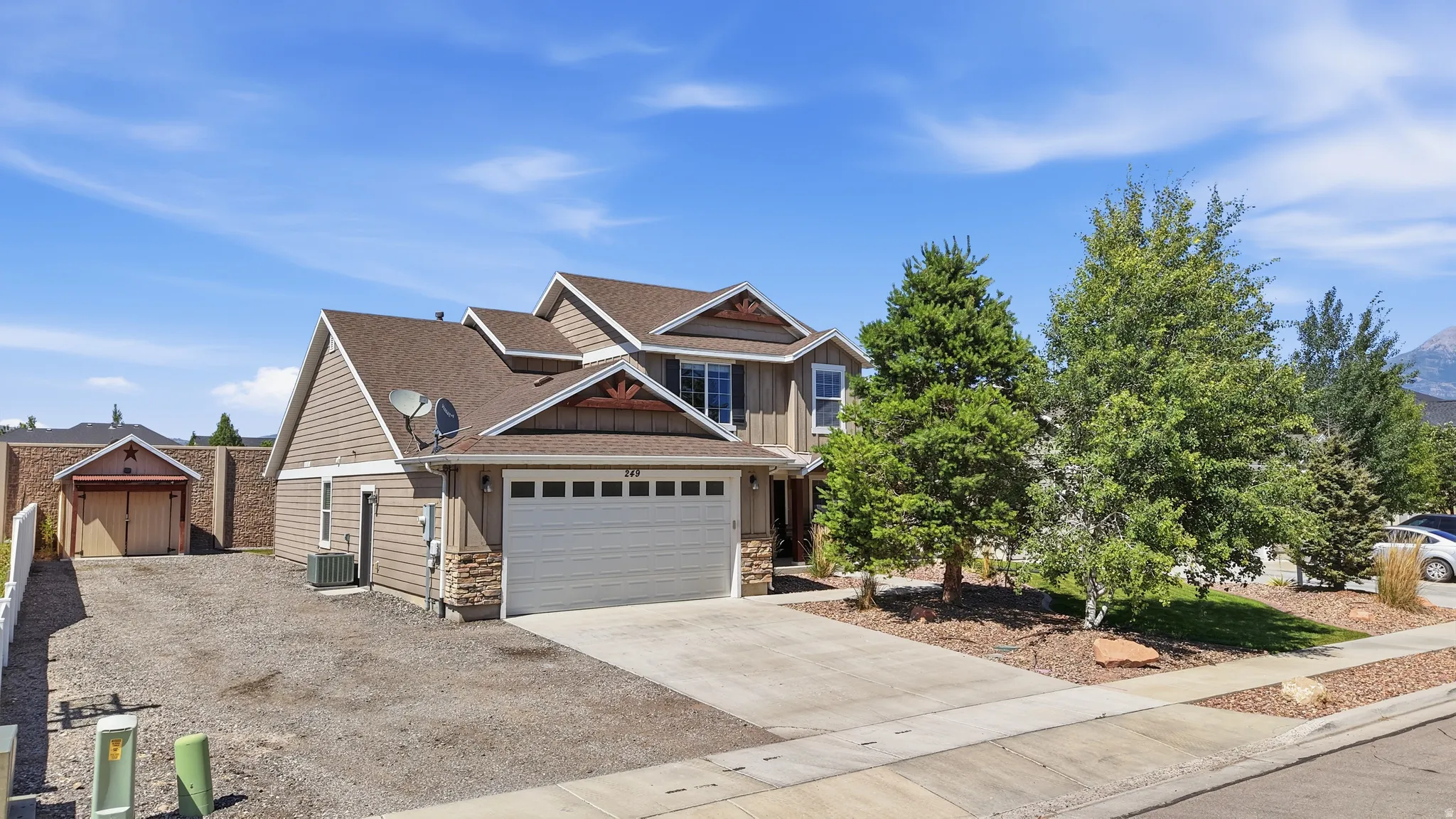 Two-story residence featuring a two-car garage, stone accents on the facade, and a side-yard shed with double doors