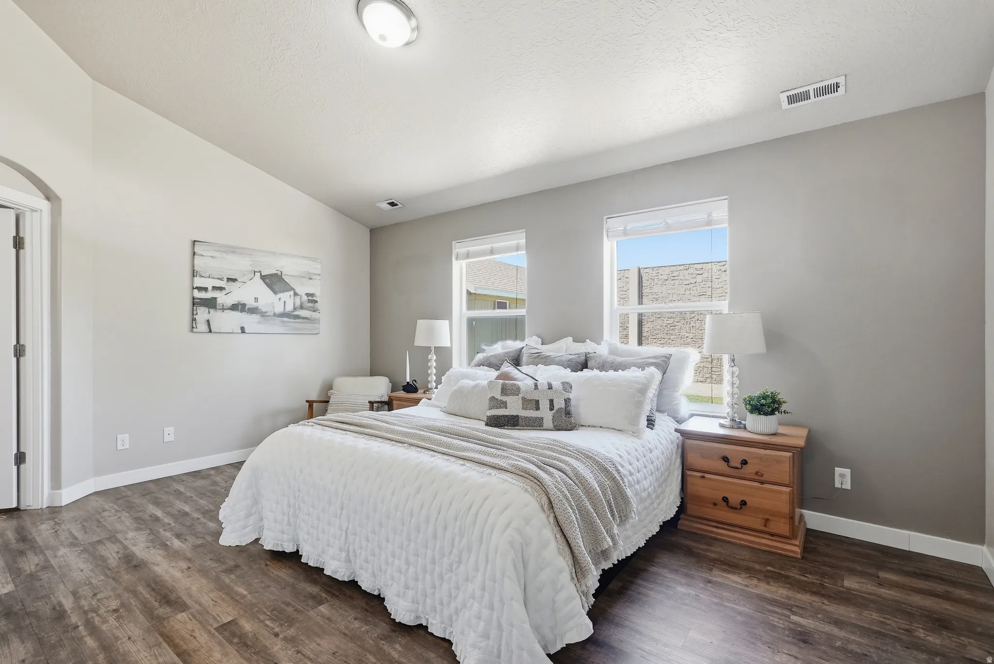 Spacious primary suite featuring wood-finish flooring and two windows with white trim