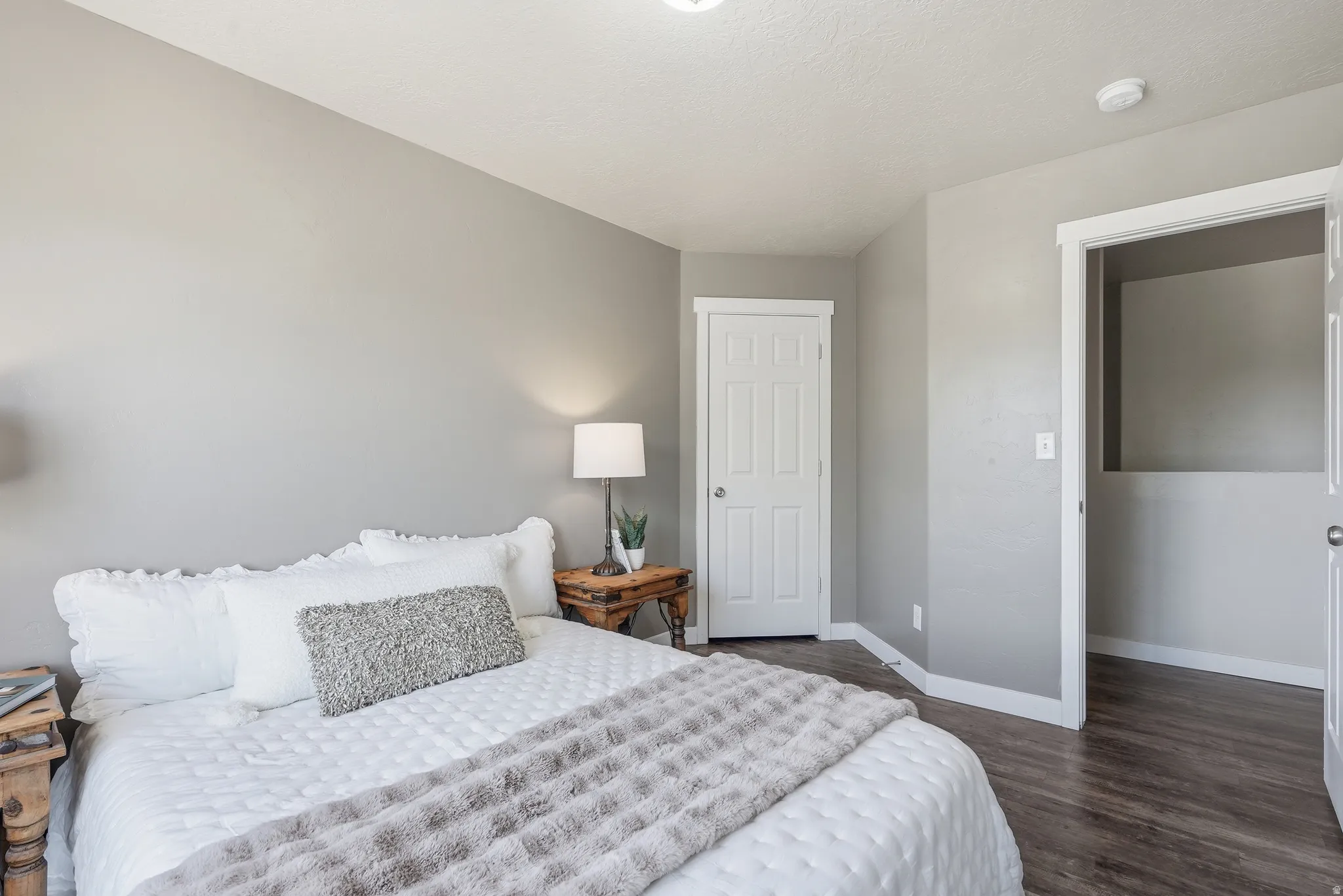Bedroom featuring neutral wall color, wood-finish flooring, white trim, and a five-panel interior door