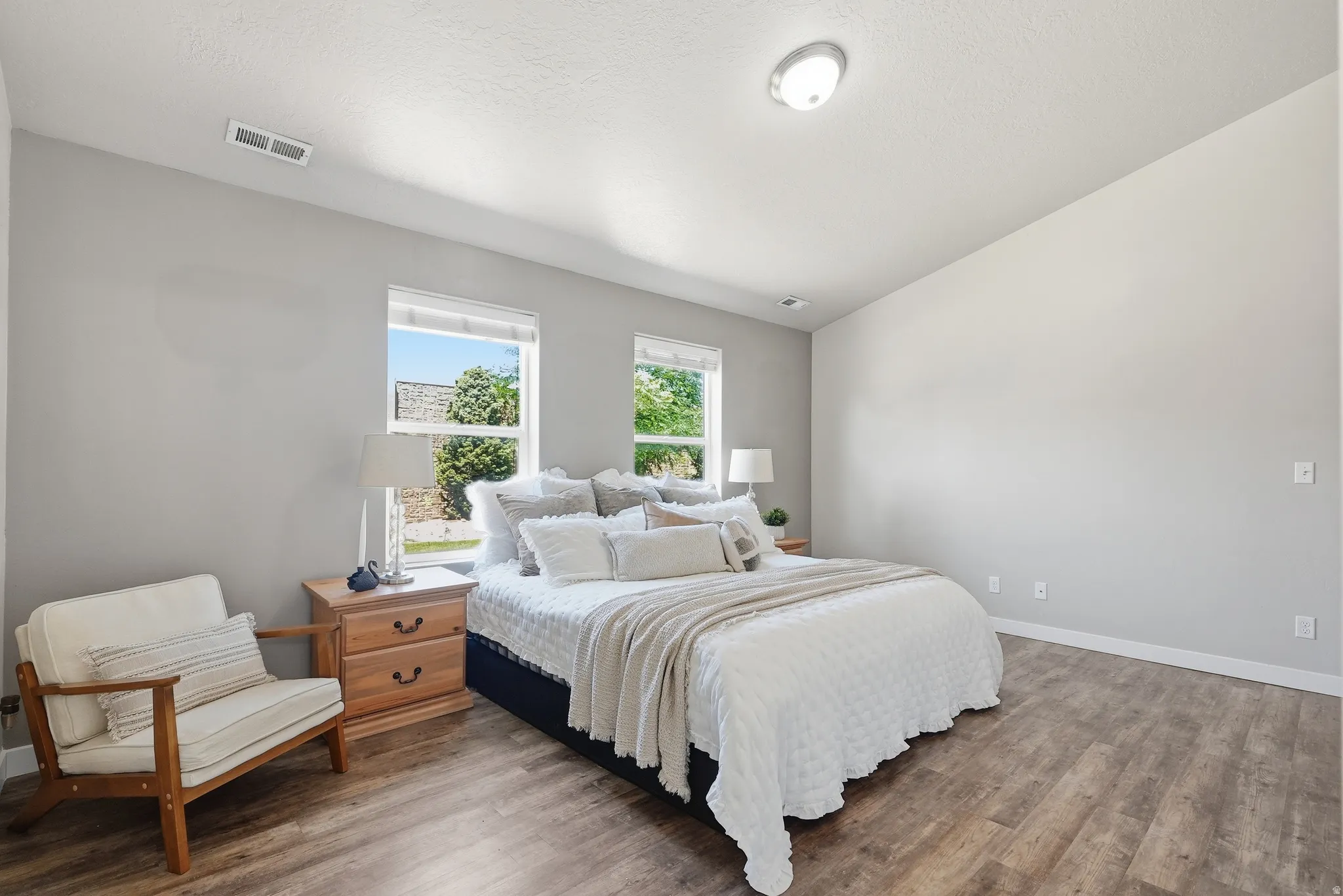 Large primary suite featuring two windows, wood-finish flooring, and abundant natural light