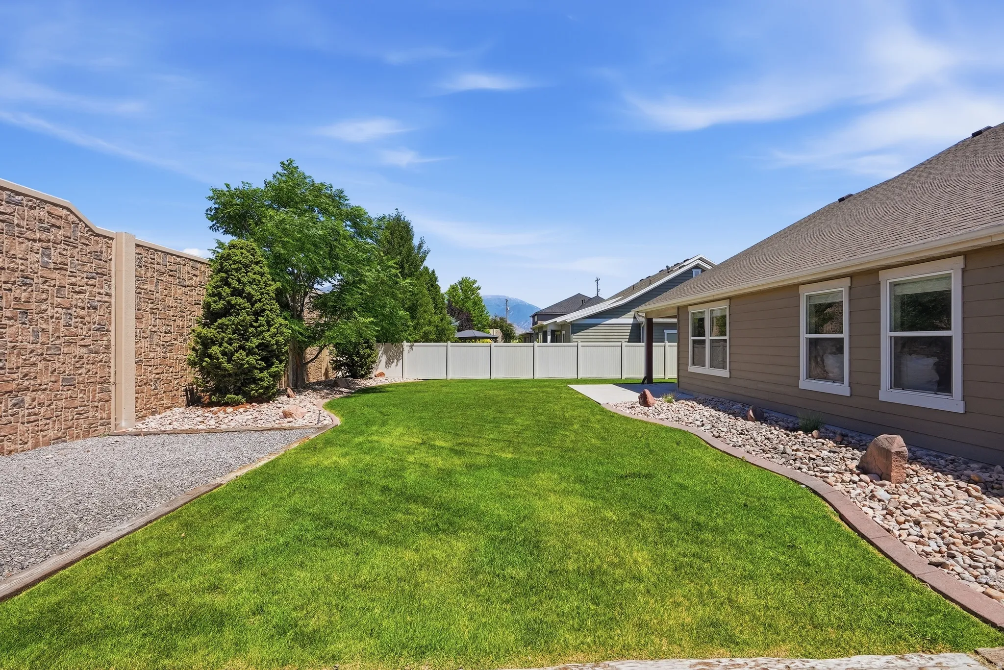 Expansive green lawn framed by decorative rock beds