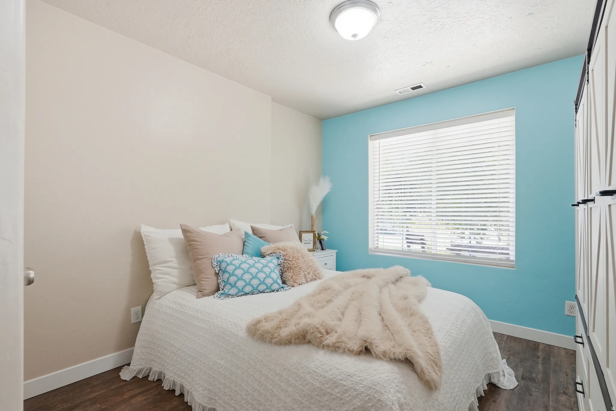 Bedroom featuring a bright accent wall, wood-finish flooring, and white trim