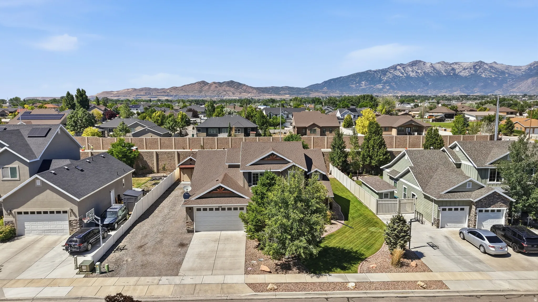 Single-family residence featuring a two-car garage, mature landscaping, and an expansive lawn with partial xeroscaping