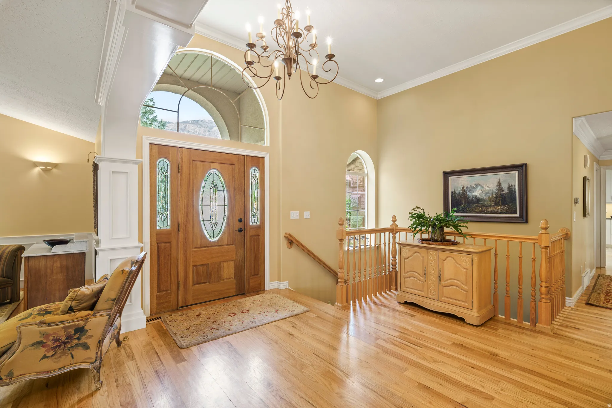 Grand entry featuring a solid wood door with decorative glass inserts, an arched transom window, and a wrought iron chandelier