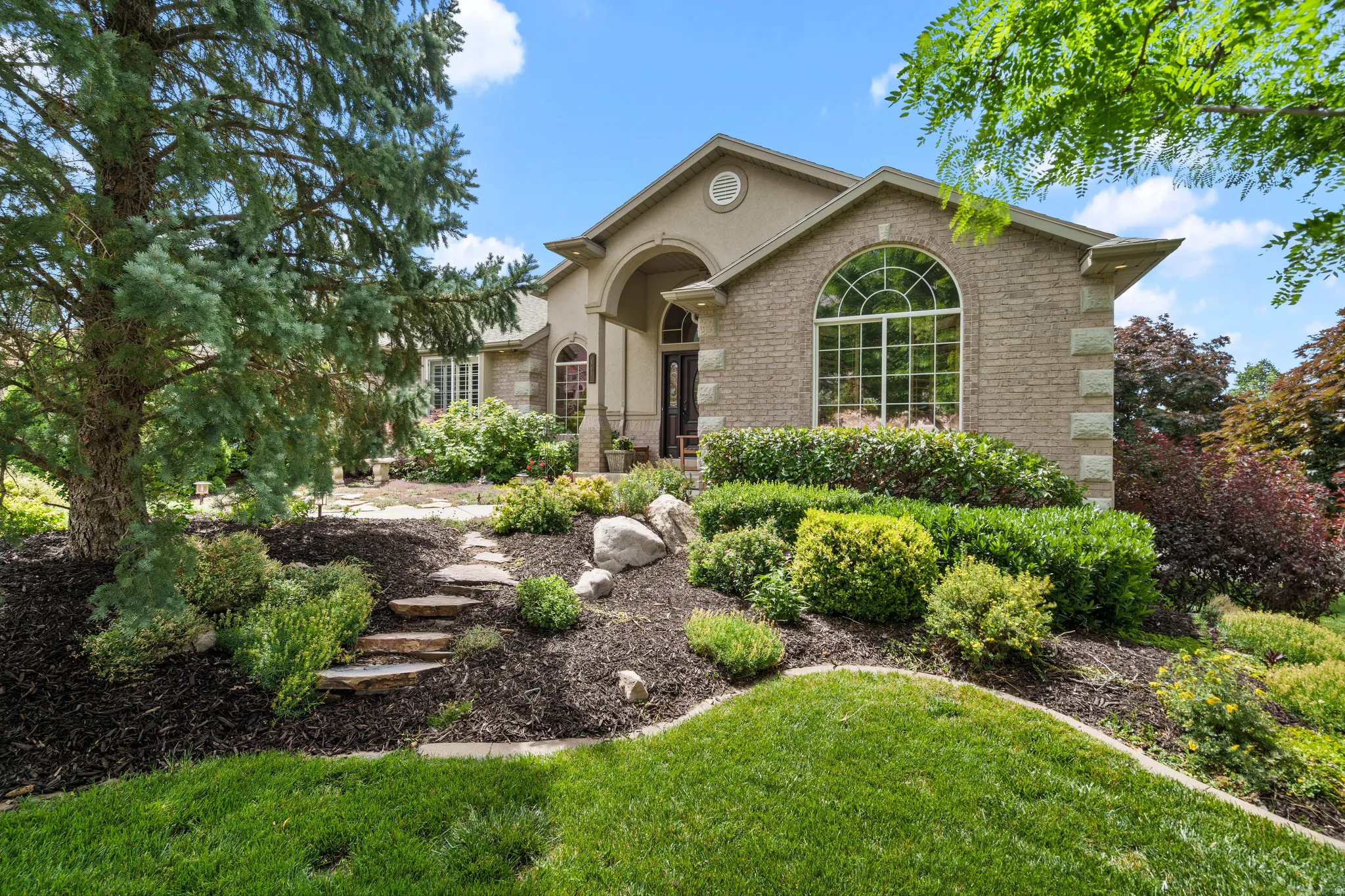 Traditional-style residence featuring a brick facade with stone accents, an arched entry.