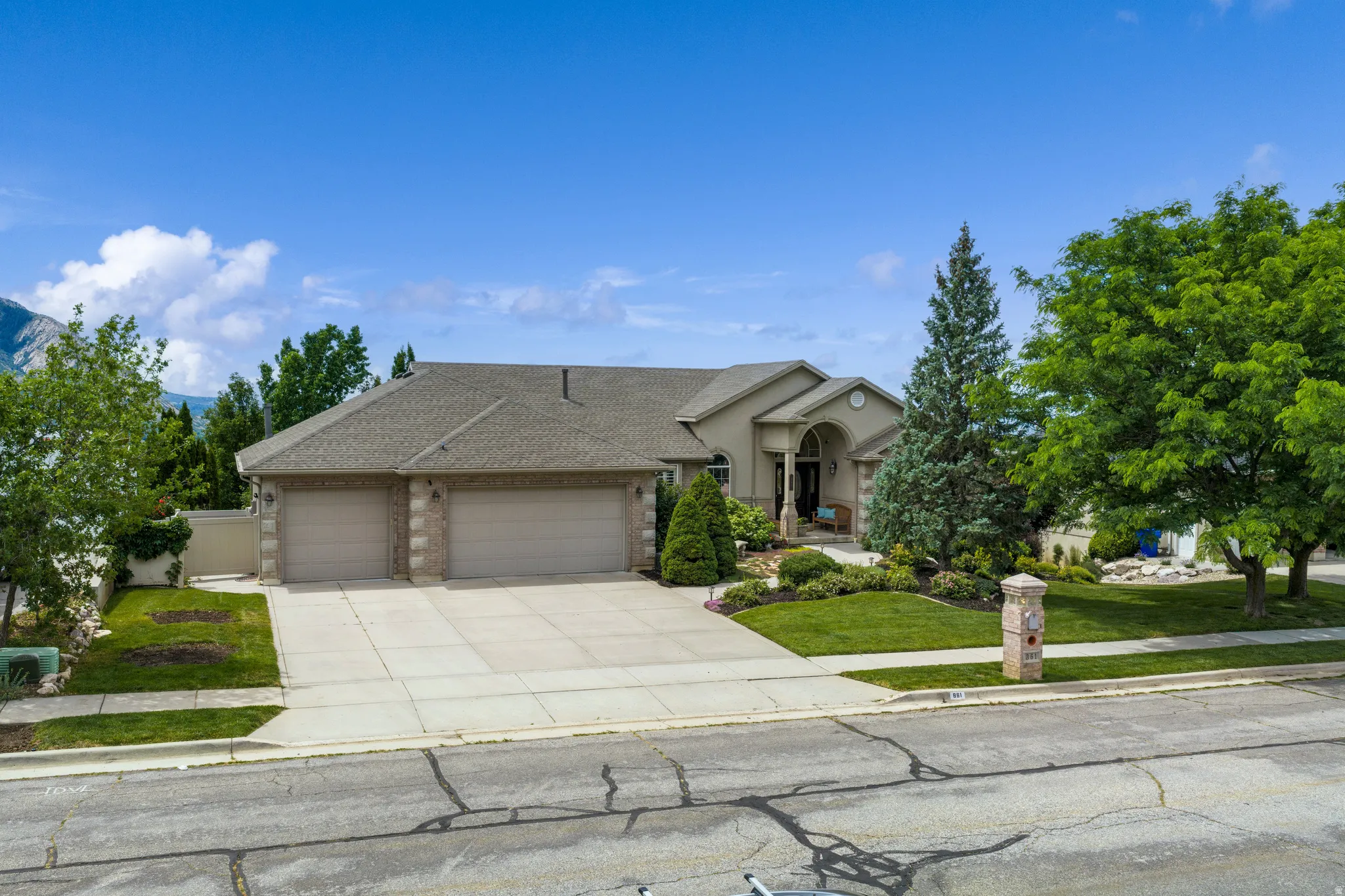 Stucco exterior residence featuring a 3-car garage with brick accents and a concrete driveway