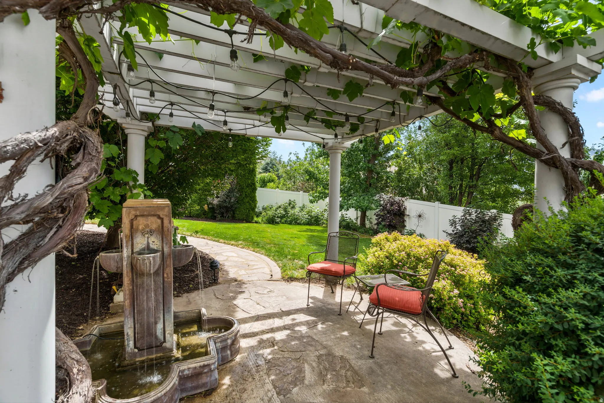 Charming pergola retreat featuring mature grapevines canopy a tiered Italian style fountain creating a peaceful setting to relax