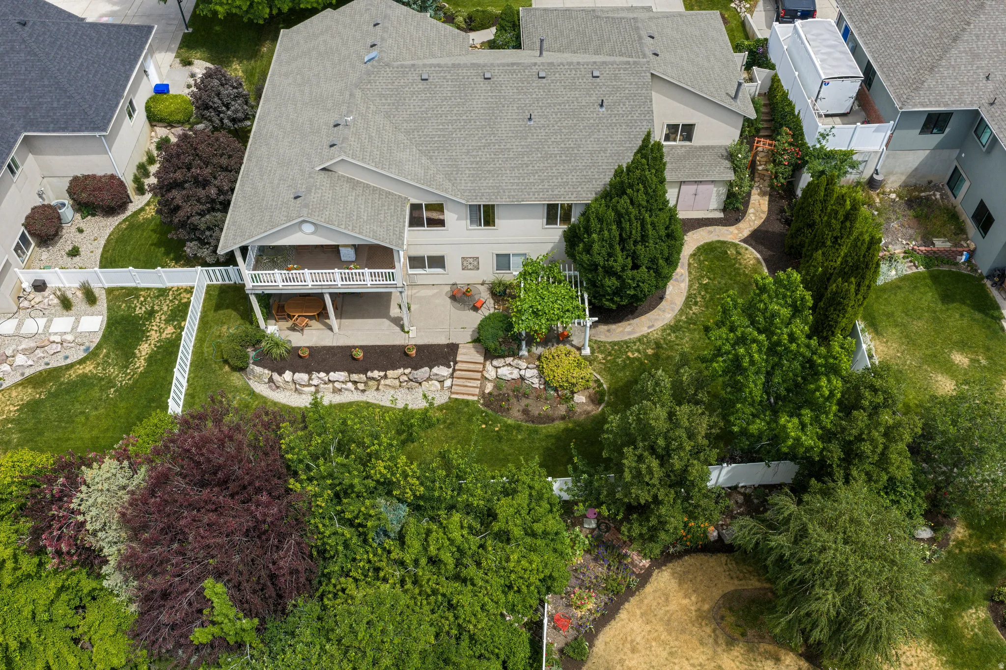 Expansive backyard featuring a multi-level design with mature landscaping, a covered patio, a second-story balcony
