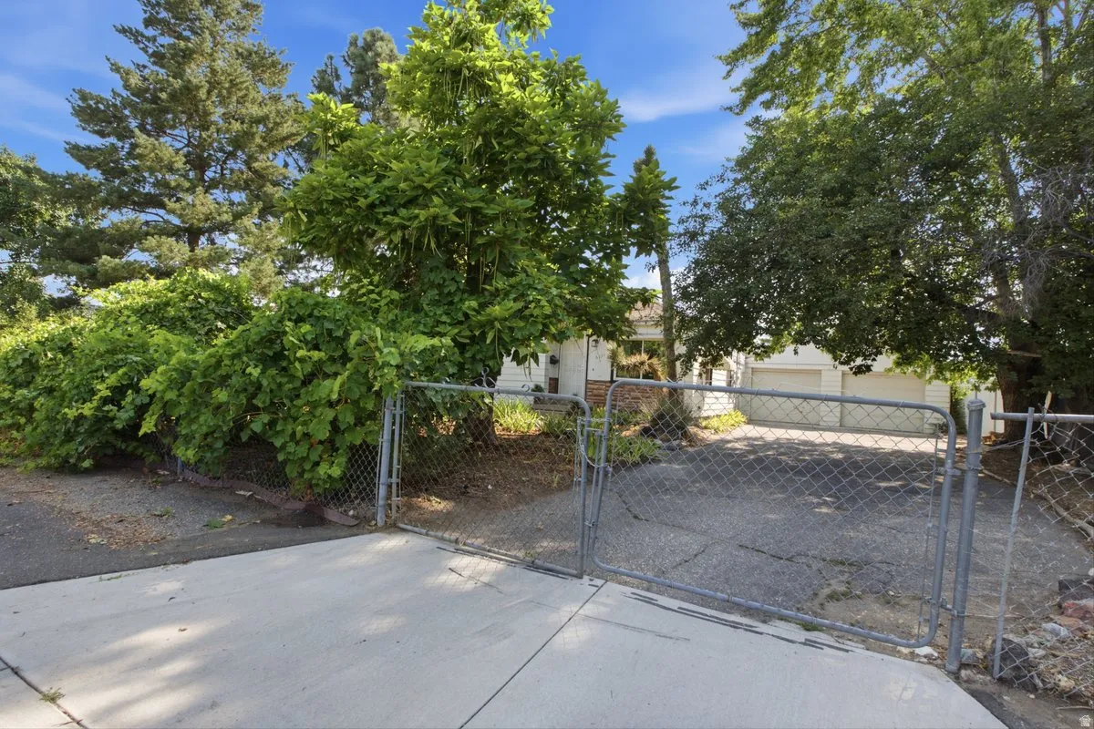 Front Gated driveway access featuring a concrete apron and chain-link fencing