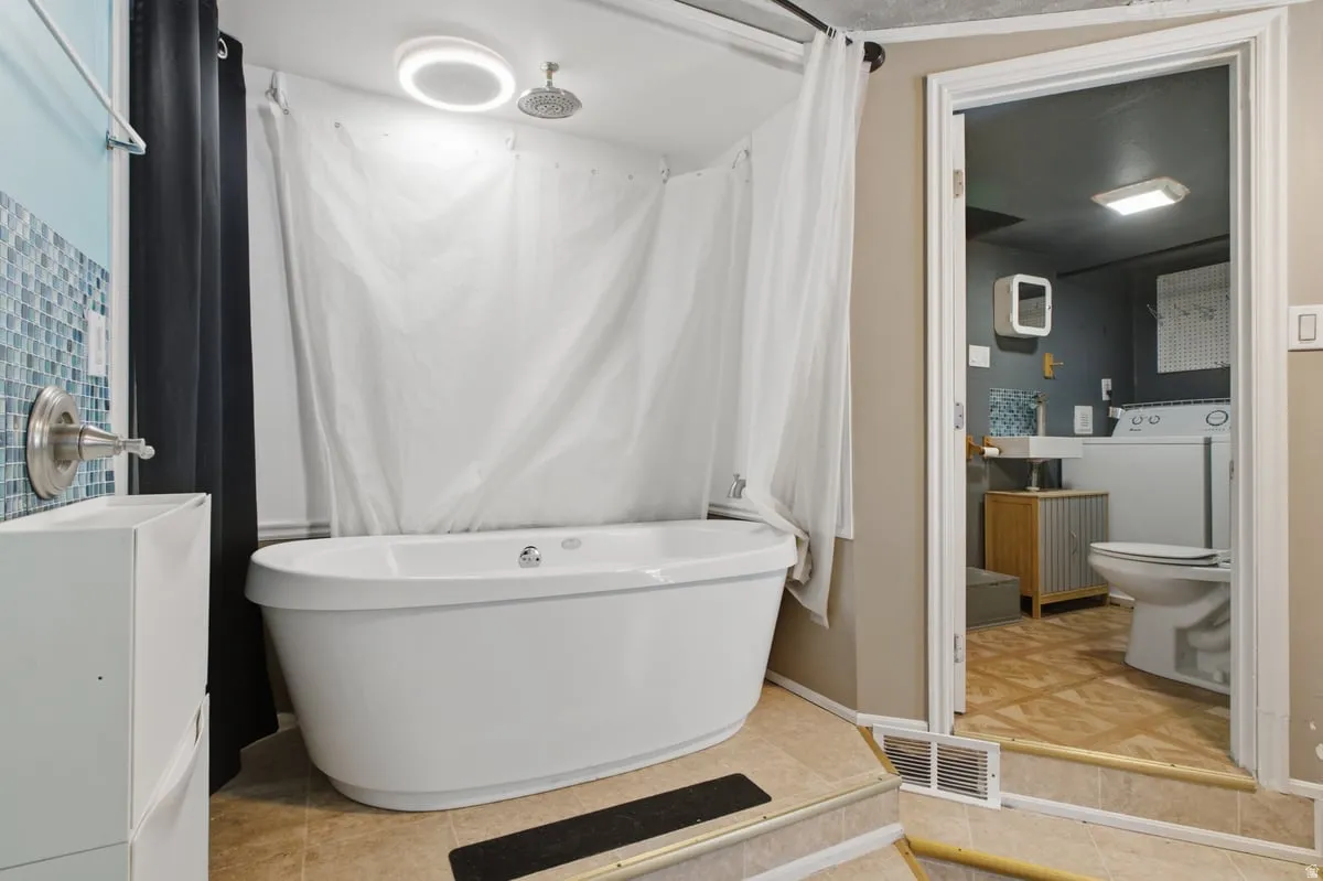 bedroom#3 Freestanding soaking tub with a rain shower head, adjacent to a vanity with a brushed nickel faucet, and mosaic tile detailing