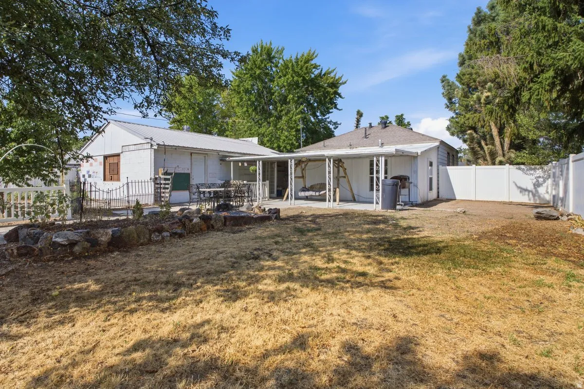 Spacious backyard featuring a covered patio, defined hardscaping, and a privacy fence