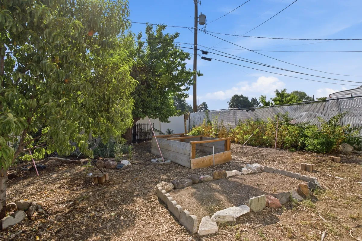 Expansive backyard featuring mature trees, a raised garden bed, and a rock-bordered planting area