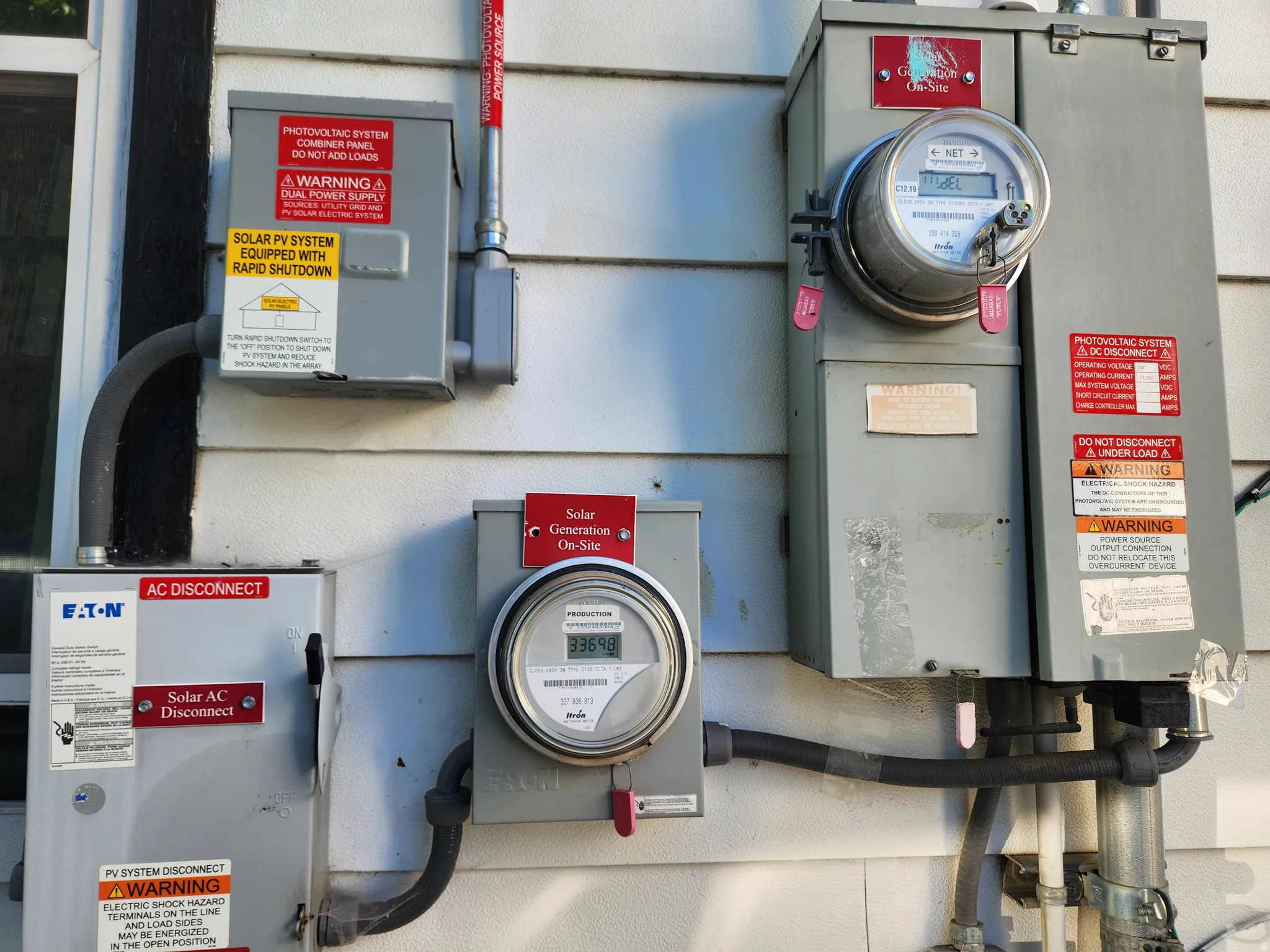 Paid off Solar Panels, 18 count, on garage roof. Exterior wall featuring a solar photovoltaic system with rapid shutdown capability and multiple utility meters