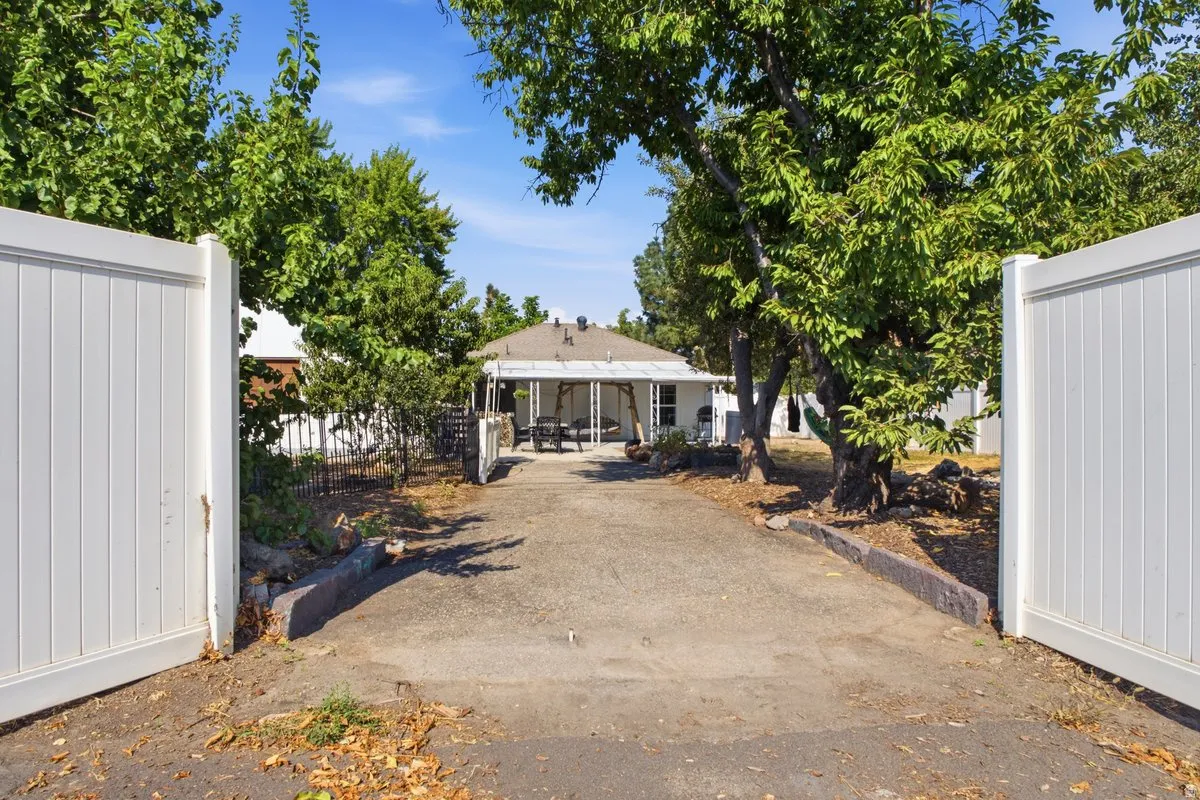 backyard entry, Gated, with white fencing, mature trees, and a covered porch