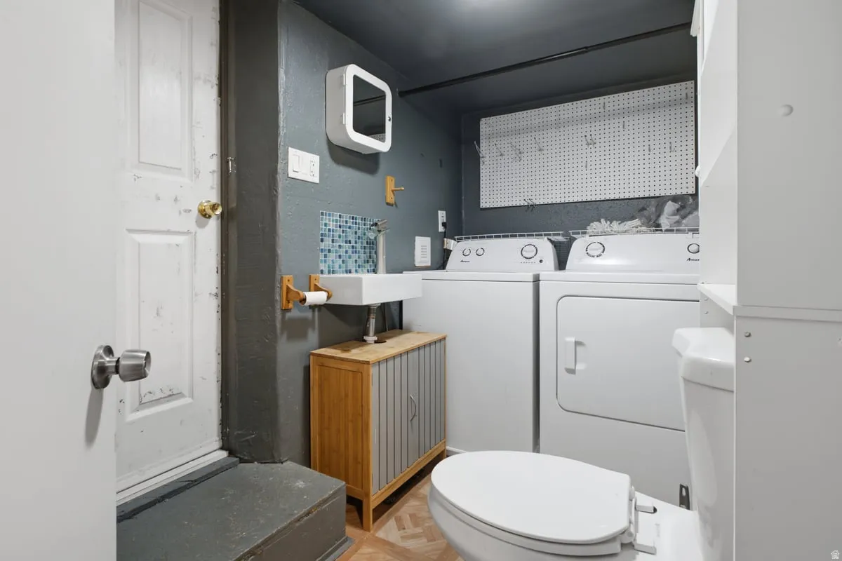 Laundry mixed with 1/2 bath. Wall-mounted sink with mosaic tile backsplash, solid wood vanity, and a side-by-side washer and dryer