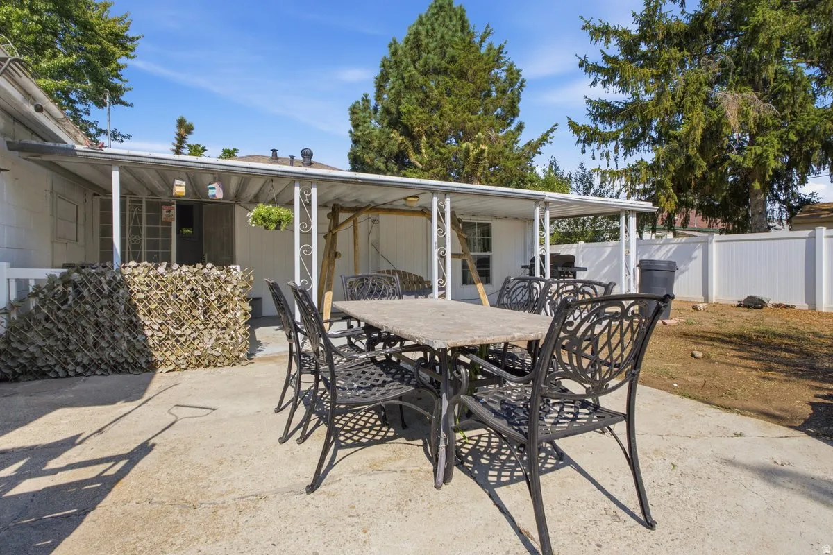 Backyard patio with a covered outdoor area and white privacy fencing