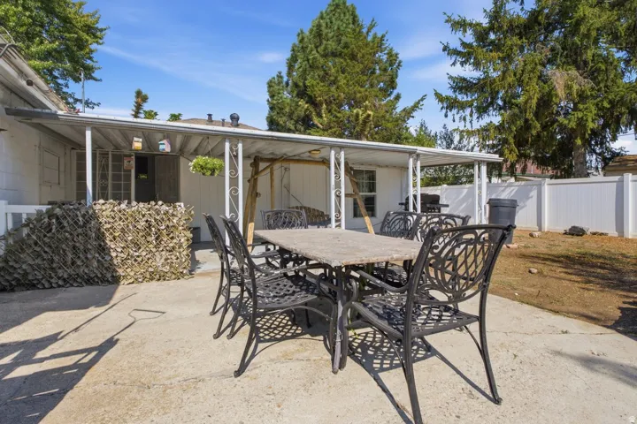 Backyard patio with a covered outdoor area and white privacy fencing