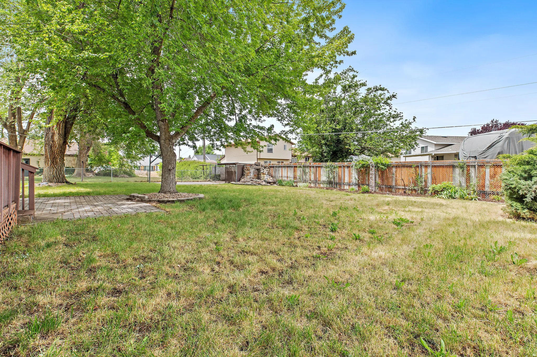 Spacious backyard featuring a brick paver patio, established trees, basketball hoop, extra storage, fountain, pond, and a wood privacy fence