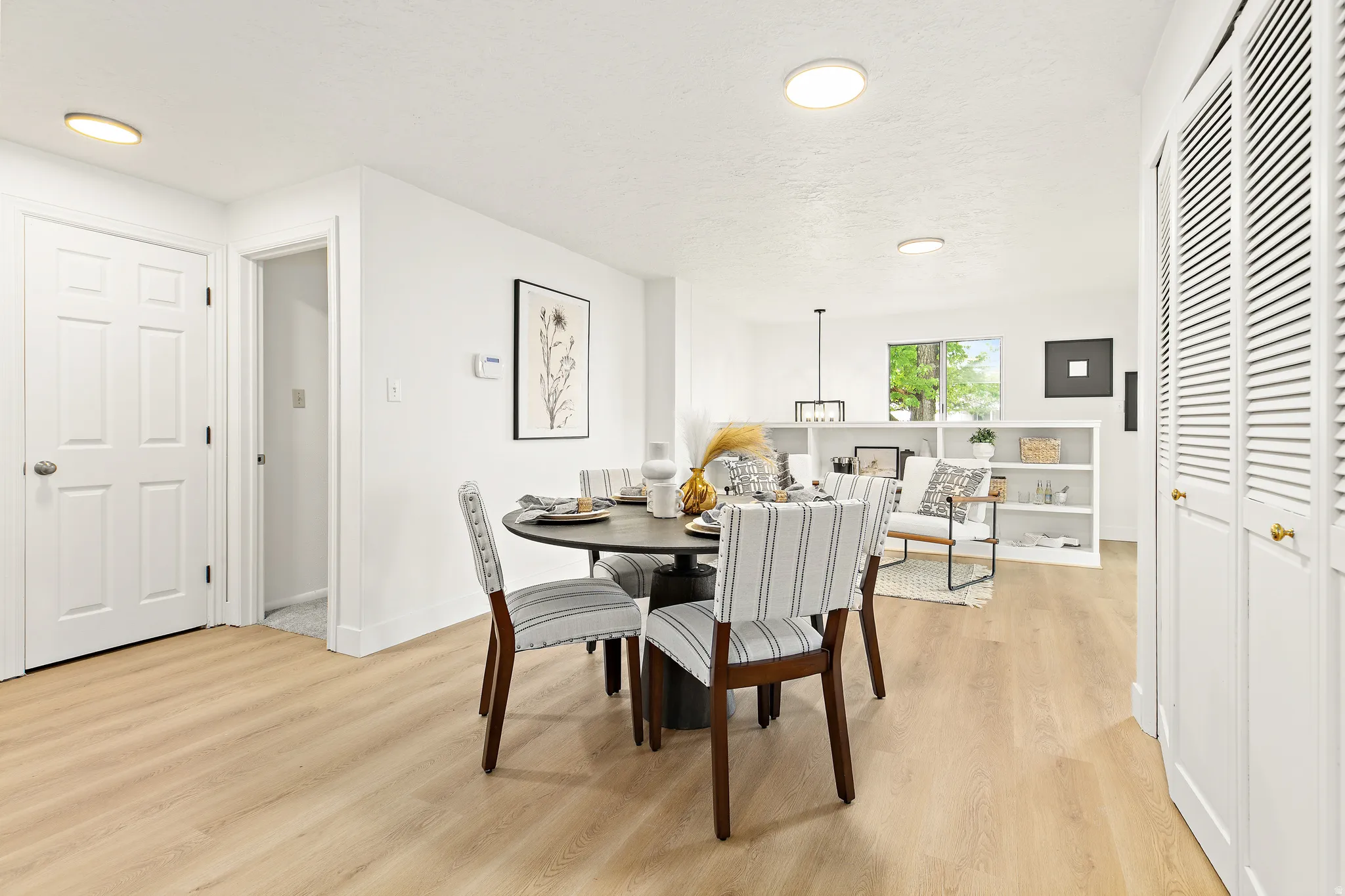 Open-concept living area featuring light wood-finish flooring, white walls, and recessed lighting