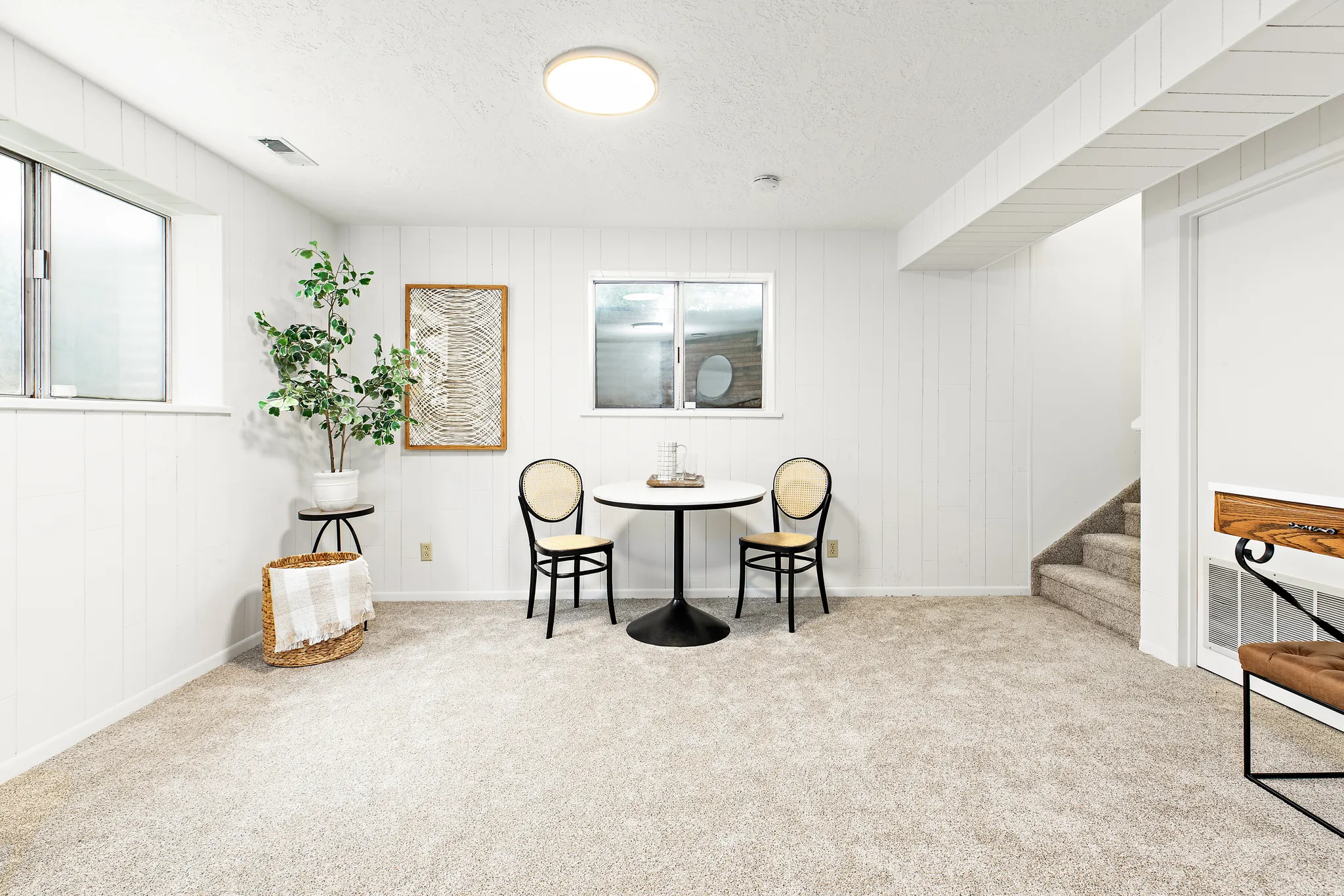 Finished room featuring soft carpet flooring, white vertical plank wall paneling, two windows, and a flush mount ceiling light