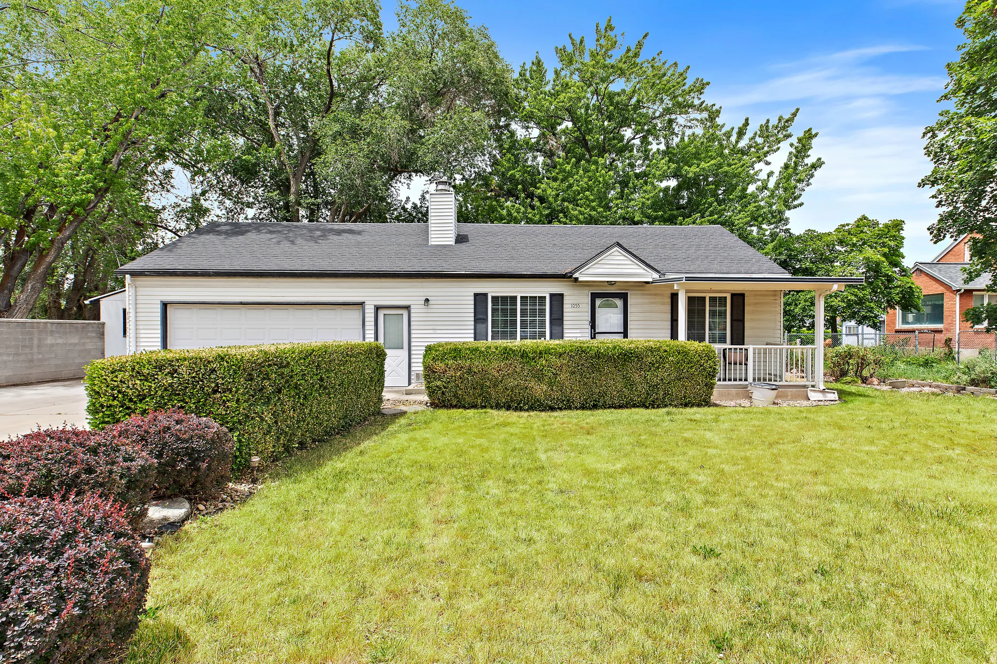 Cream-colored siding residence featuring a front lawn and mature landscaping