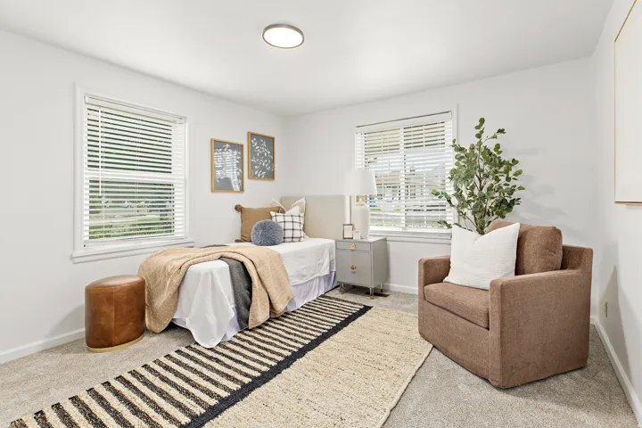 Bedroom featuring two windows with blinds, light gray wall-to-wall carpeting, and a flush-mount ceiling light fixture