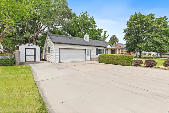 Property exterior featuring white siding, a prominent two-car garage, a separate storage shed, and a concrete driveway