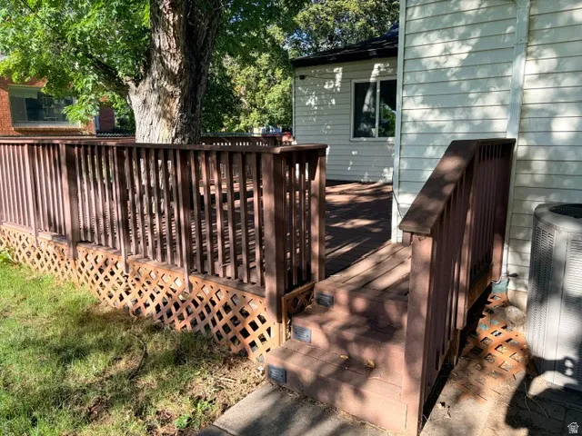 Wood-finish deck with steps, complete with railing and lattice skirting, offering exterior access