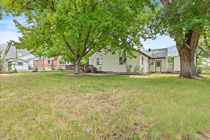 Expansive grassy yard area with mature trees and a rear deck