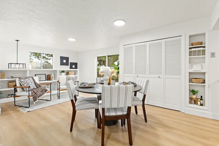 Open-concept living space featuring wood-finish flooring, recessed lighting, built-in shelving, and louvered bifold doors