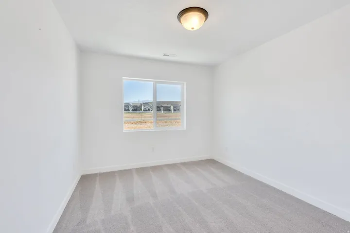 Room featuring light gray patterned carpeting, white walls, a single window, and a flush mount ceiling light fixture