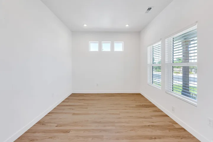 Spacious room featuring wood-finish flooring, white walls, and recessed lighting