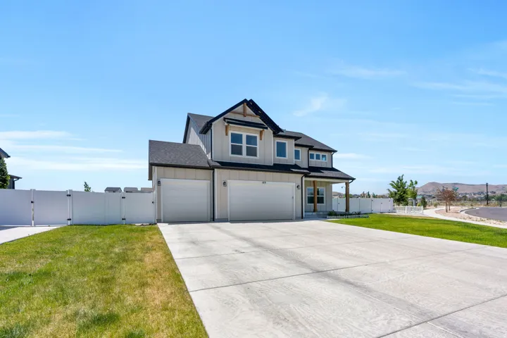 Modern residence featuring a two-car garage, a covered porch with wood columns, and a light-toned exterior with dark trim