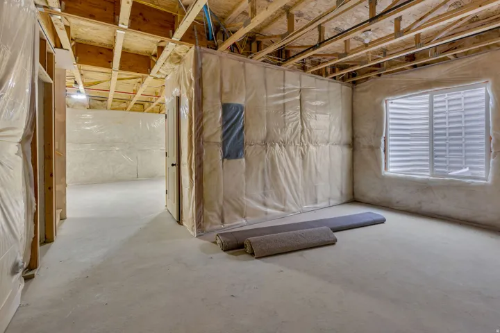 Unfinished basement with exposed ceiling joists and concrete flooring
