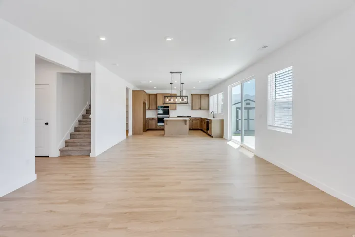 Open-concept living area featuring light wood-finish flooring, recessed lighting, and a neutral color palette